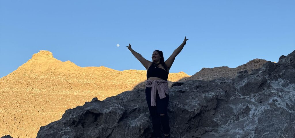 Mujer con los brazos abiertos mirando el cielo de san pedro de atacama en el tour vallecito